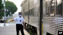 2022 年 9 月 15 日,在伊利诺伊州阿灵顿高地的梅特拉阿灵顿高地站,一名客运火车列车员发出放行信号。(美联社照片)