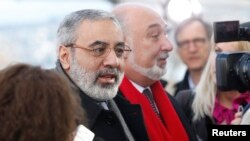 Bộ trưởng Thông tin Syria Omran Zoabi (L) nói chuyện với một nhà báo khi ông đến để dự cuộc họp với Đặc sứ Lakhdar Brahimi ở Geneve, 24/1/14