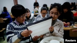 资料照: 在北京一所大学,学生们在练习如何把HEPA过滤网装在风扇上,以自制空气净化器。