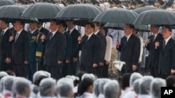 资料照片:中共总书记习近平、中国总理李克强、中共政治局常委张德江、俞正声、王岐山等人在雨中在人民英雄纪念碑前唱国歌。(2013年10月1日)