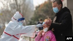 中国武汉的医务人员在给一个女孩进行核酸检测。(2020年3月5日)