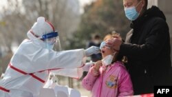 中国武汉的医务人员在给一个女孩进行核酸检测。(2020年3月5日)