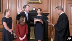 美国最高法院首席大法官约翰·罗伯茨在最高法院带领卡瓦诺宣誓就任大法官。阿什利·卡瓦诺捧着圣经,他们的女儿在场。