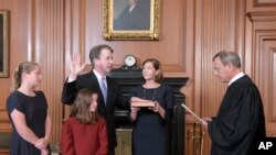 美国最高法院首席大法官约翰·罗伯茨在最高法院带领卡瓦诺宣誓就任大法官。阿什利·卡瓦诺捧着圣经，他们的女儿在场。