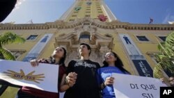 来自阿根廷的非法移民帕谢罗(中),他的母亲萨沙(右)以及他的女友,一名移民问题活动人士莫拉加(左)在迈阿密市中心的自由塔前举着标语