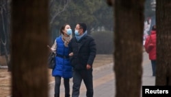 在雾气笼罩的下午,一对相爱男女戴口罩走在北京街头。(2014年2月24日)