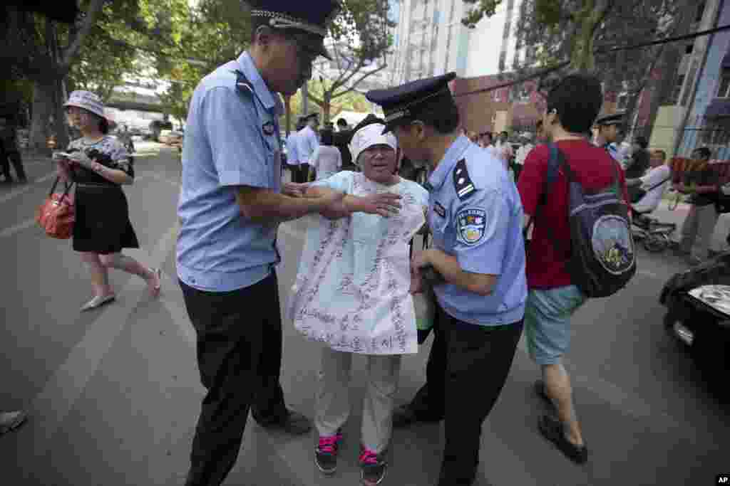 Công an Trung Quốc kéo một phụ nữ ra khỏi tòa án thành phố Tế Nam, tỉnh Sơn Đông. Biểu ngữ của bà này có từ “bất công.”