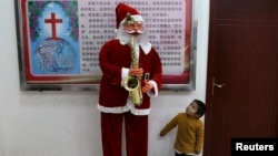 2018年12月22日,中国云南省鹿泉彝族苗族自治县的基督教堂,一个男孩看着圣诞老人像。