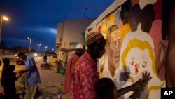 2013年6月25日,壁画艺术家索莱耶(中)绘制欢迎美国总统奥巴马来访的壁画并让一名儿童在壁画上印上小手印。