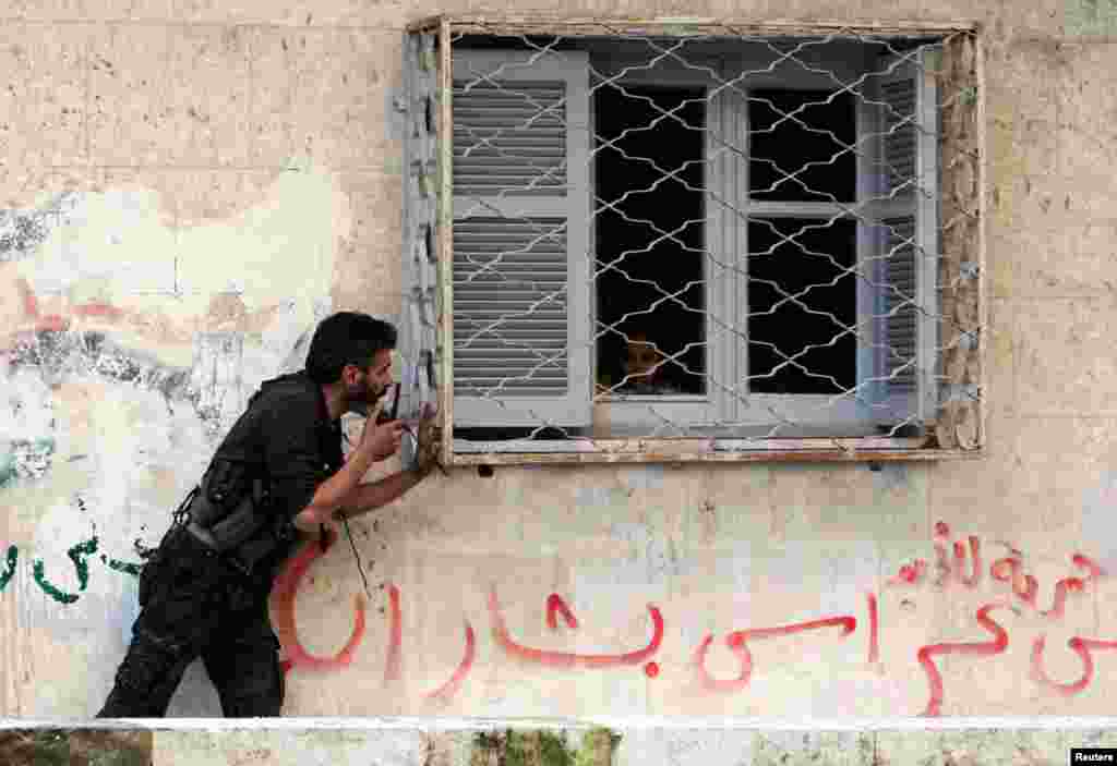 Một thành viên của Quân đội Giải phóng Syria yêu cầu một đứa trẻ tránh đứng gần cửa sổ vì lý do an ninh tại thị trấn Bustan al-Qasr trong thành phố Aleepo ngày 30/12/2012.