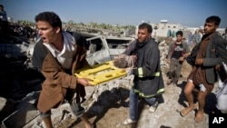 在也门,人们抬着死难者的尸体在废墟上走过。