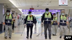 资料照:戴着口罩的工作人员在台北桃园机场喷洒消毒药水防范新冠病毒。(2020年1月22日)