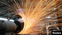 浙江杭州市一名戴着口罩的工人在生产自行车轮子钢圈的生产线上工作。（2020年3月2日）