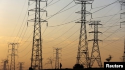 资料照:2023年1月16日,在南非索韦托奥兰多,一名男子在南非Eskom电力公司因燃煤电厂老化而频繁停电的电力塔下行走。