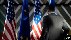 资料照:一名工作人员在布鲁塞尔欧洲委员会办公楼里检查欧盟与美国旗帜。(2023年4月4日)