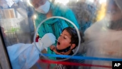 印度一位医护人员在对一名儿童进行新冠病毒感染检测。(美联社图片)