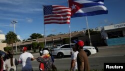 美国佛罗里达州迈阿密,人们手举美国和古巴国旗走过一家古巴风味的餐馆。(2021年7月18日)