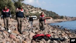 土耳其军警站在恰纳卡莱省艾瓦哲克城附近海滩上的一名移民尸体旁。(2016年1月30)