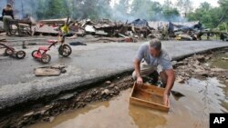 马克·莱斯特6月24日在所居住的西弗吉尼亚州白硫磺泉镇遭遇严重洪水之后,正在进行清理,用溪水清洗一个盒子。