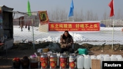 春节前北京一个露天广场内一名男子在售卖桶装白酒。(2025年1月22日)