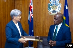 澳大利亚外交贸易部发布照片显示,澳大利亚外长黄英贤向到访的所罗门群岛总理杰里迈亚·马内莱(Jeremiah Manele)赠送礼物。(2024年6月5日)