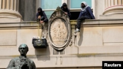 在哥伦比亚大学,一名学生抗议者从汉密尔顿楼的一座阳台把装着食物的框子吊上来。(2024年4月30日)