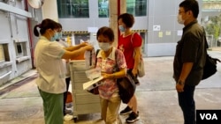 香港卫生署人员8月3日早上在港岛南区香港仔赛马会诊所,派发武汉肺炎病毒深喉唾液测试包,约100名市民清晨7时半前到场轮候。 (美国之音/汤惠芸)