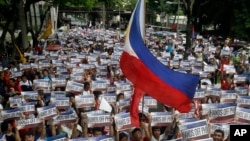 在菲律宾首都马尼拉以东的金融区马卡蒂市,抗议者举行独立日集会,高举标语,游行走向中国领事馆前。(2015年6月12日)