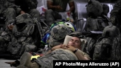 资料照片:美国陆军第三装甲团的军人在巴格达萨瑟空军基地客运航站内小憩。(2011年8月2日)