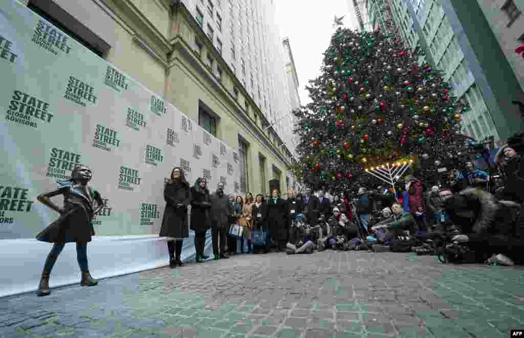 无畏女孩像在她的新家——纽约证券交易所旁边亮相,人们参加揭幕活动。(2018年12月10日) 。