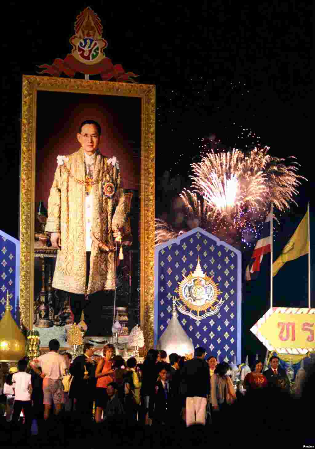 A portrait of Thailand's King Bhumibol Adulyadej (L) adorns a stage as fireworks explode over Bangkok, Dec. 5, 1999, in celebration of the king's 72nd birthday.