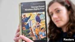 伦敦一家书店女职员手持英国作家乔治·奥威尔著作《1984》。描写集权政府对个人监控无所不在的名著《1984》于1949年6月8日出版,在2013年重回畅销书排行榜。(2013年6月9日)