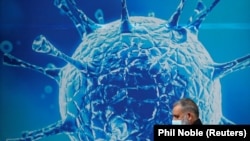 一名英国戴口罩路人经过当地科学中心的宣传画 (照片来自路透社 REUTERS/Phil Noble)