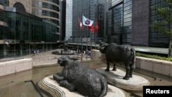 资料照:香港交易广场水牛雕塑前香港证券交易所的旗子在飘扬。(2015年5月28日)