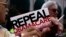 Sekelompok kecil pengunjuk rasa menyuarakan keinginan mereka agar Pemerintah AS membatalkan layanan kesehatan terjangkau yang lebih populer dengan sebutan Obamacare, dalam aksi di Indianapolis, Indiana, 26 Agustus 2013 (Foto: dok).
