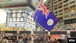 反送中运动6-12一周年十八区街头展览,在铜锣湾展览场地有人高举港英殖民时代香港旗帜。