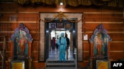 一名工作人员在孟买的一个印度教寺庙进行消毒,以避人们感染新冠病毒。图片:2020年11月15日