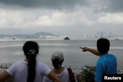 FILE - A tourist points China's Xiamen from a former military fort, ahead of the 60th anniversary of Second Taiwan Straits Crisis against China, on Lieyu island, Kinmen county, Taiwan, Aug. 20, 2018.