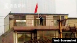 网上流传的贾敬龙家被拆时的照片,贾敬龙举红旗站在楼上