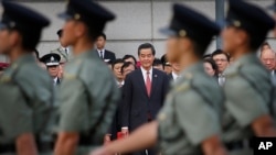 Trưởng quan Hành chính Lương Chấn Anh xem quân đội diễu hành trong lễ thượng kỳ ở Hong Kong trong khi hàng ngàn người biểu tình từ phía sau hàng rào chắn của cảnh sát la ó đòi ông từ chức.