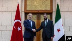 တူရကီနိုင်ငံခြားရေးဝန်ကြီး Hakan Fidan(ဘယ်) နဲ့ ဆီးရီးယား HTA သူပုန်အဖွဲ့ခေါင်းဆောင် Ahmad al-Sharaa(ယာ)တို့ ဆီးရီးယားနိုင်ငံ Damascus မြို့မှာတွေ့ဆုံစဥ်၊ ဒီဇင်ဘာ ၂၂၊ ၂၀၂၄