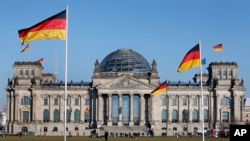 德国国会大厦,大厦前和大厦上飘扬着德国国旗。