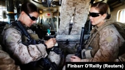 资料照片:美国海军陆战队第八团第一营的妇女接触事务队队长希娜·亚当中士(左)与医务兵珊农·克罗利坐在装甲车内准备离开她们位于阿富汗赫尔曼德省的基地，外出执行任务。(2010年11月13日)