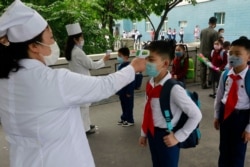资料照:朝鲜首都平壤一所小学的学生带着口罩接受体温检测。(2020年6月3日)