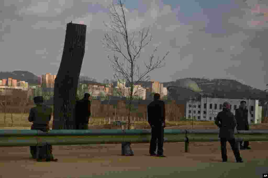 几个朝鲜人2013年4月9日在一条通往平壤的公路边上站着。