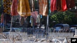 在国际妇女节这一天,在仰光街头,缅甸防暴警察列队站在路障前,抗议者高高张挂女性服装。(2021年3月8日)