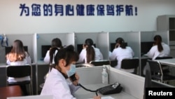 中国辽宁省沈阳市精神健康热线电话服务站里戴着口罩的辅导人员为打来求助电话的人提供帮助。(2020年2月12日)