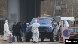 北京房山地区发现非洲猪瘟后,身穿防护服的防疫人员在通往出现疫情的村庄道路上设卡。(2018年11月23日)