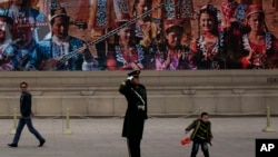 中共18届三中全会期间天安门广场的巨大屏幕、执勤武警和拿着中国国旗的小男孩。维族人民真像屏幕上那么幸福吗?