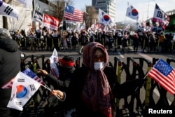韩国总统尹锡悦的支持者手持美韩国旗在首尔总统府附近举行示威反对弹劾总统。（2025年1月9日）